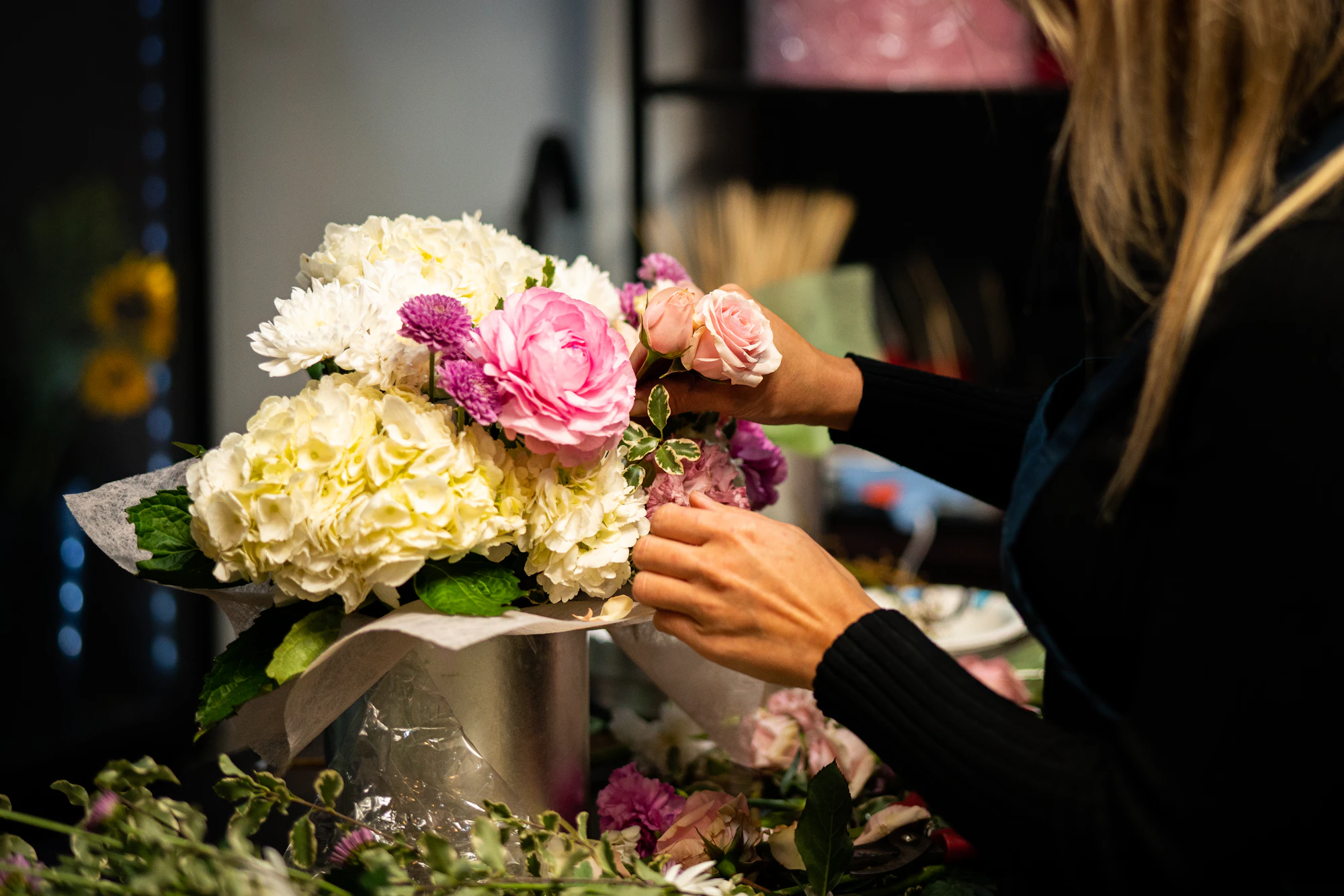 Floristin bindet einen Strauß aus Rosen und Hortensien